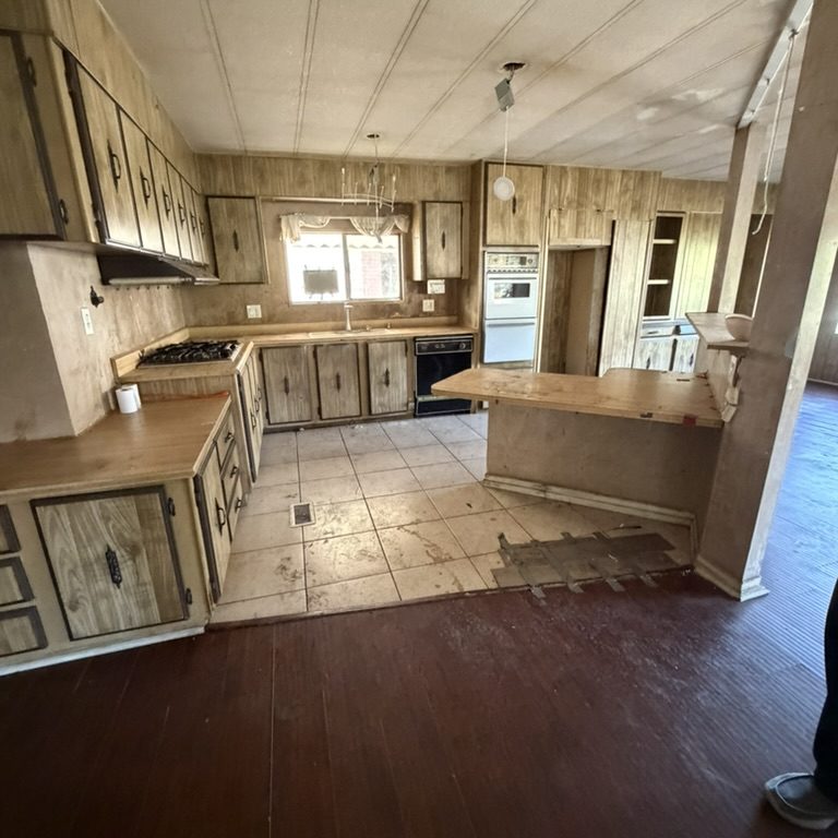 Interior of an older manufactured home with worn flooring and cabinets that may need repairs.